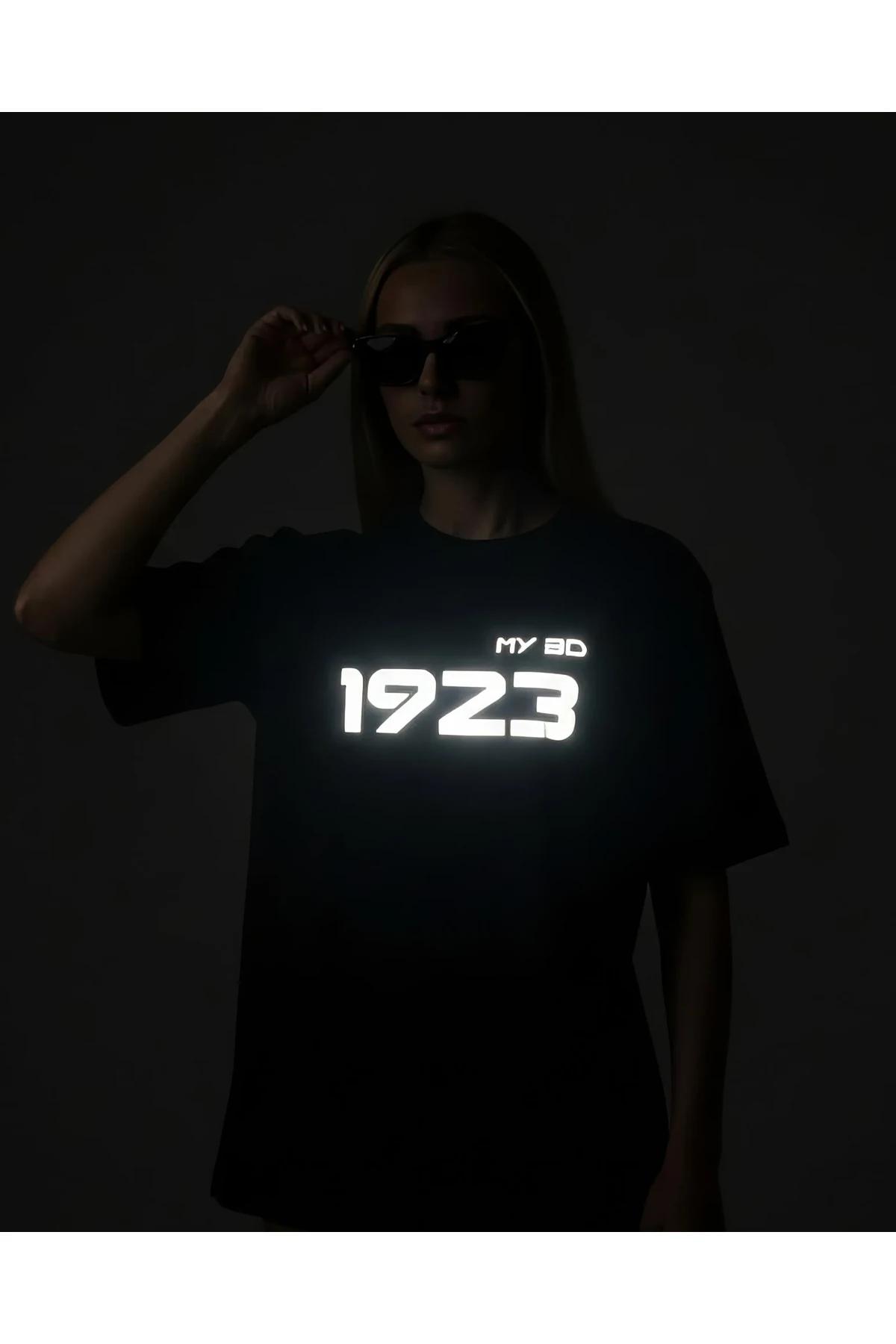 black cotton blend oversized t-shirt with retroreflective number print glowing white on chest in low light