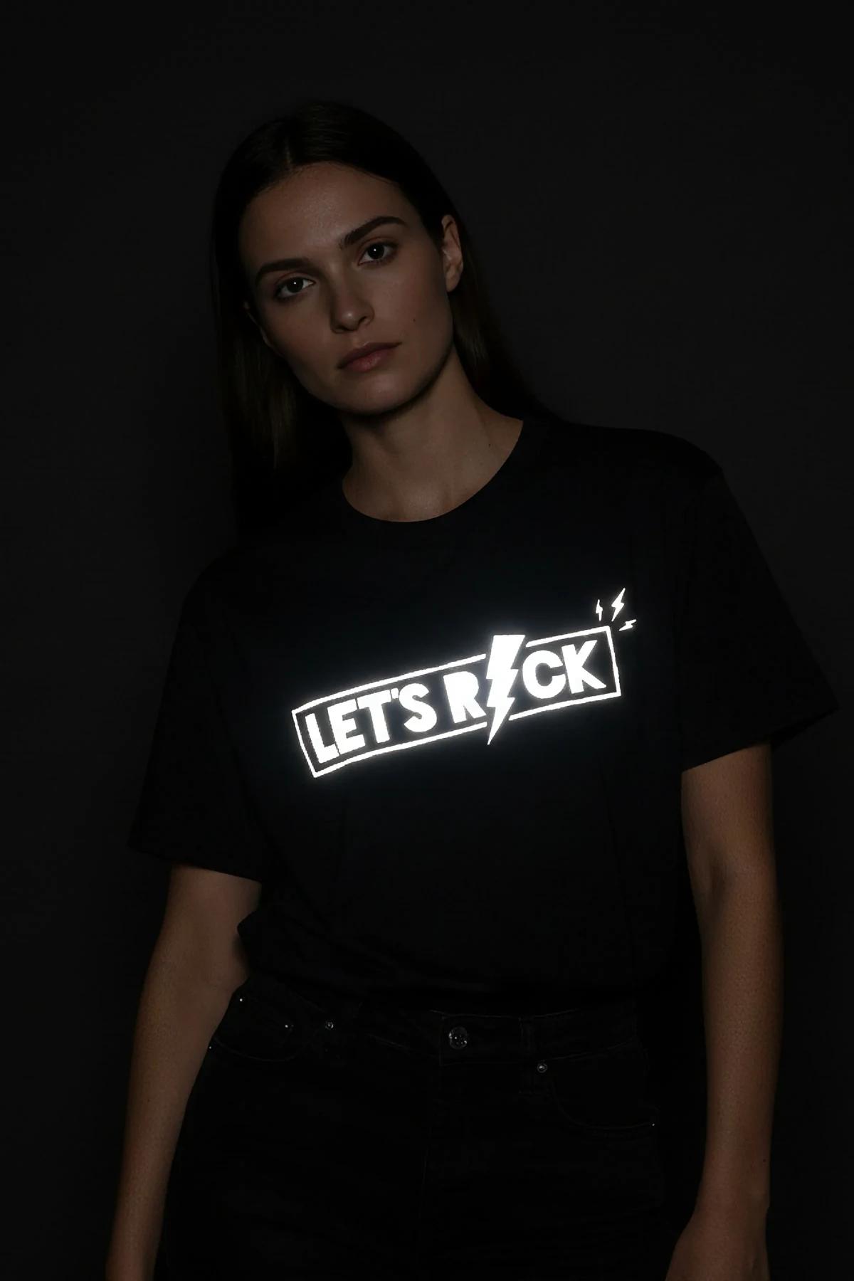 black reflective graphic t-shirt with Let's Rock lightning bolt print glowing silver-white under light, relaxed boxy fit