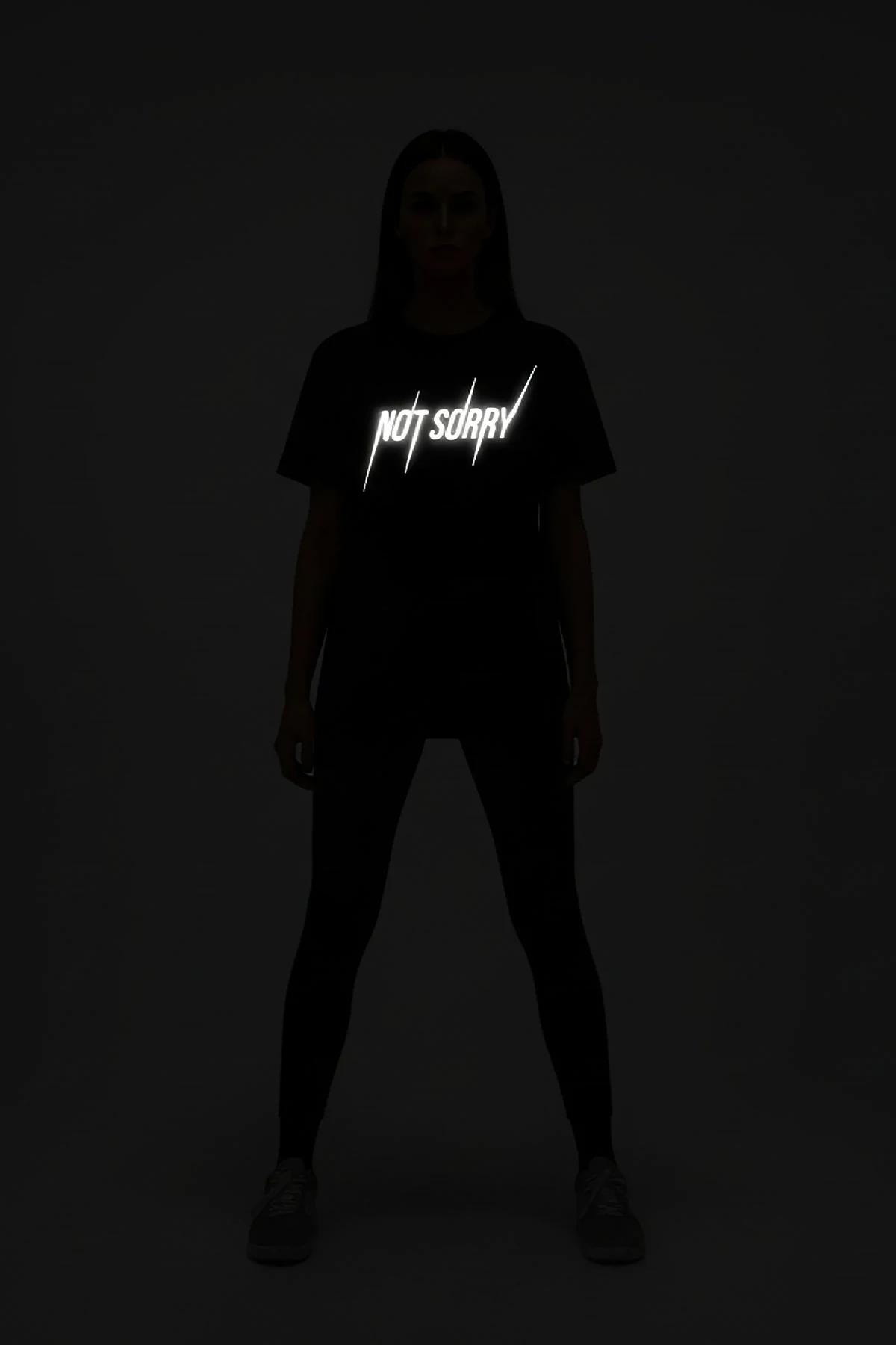 black reflective graphic tee NOT SORRY bold chest print glowing white lettering on dark background oversized fit