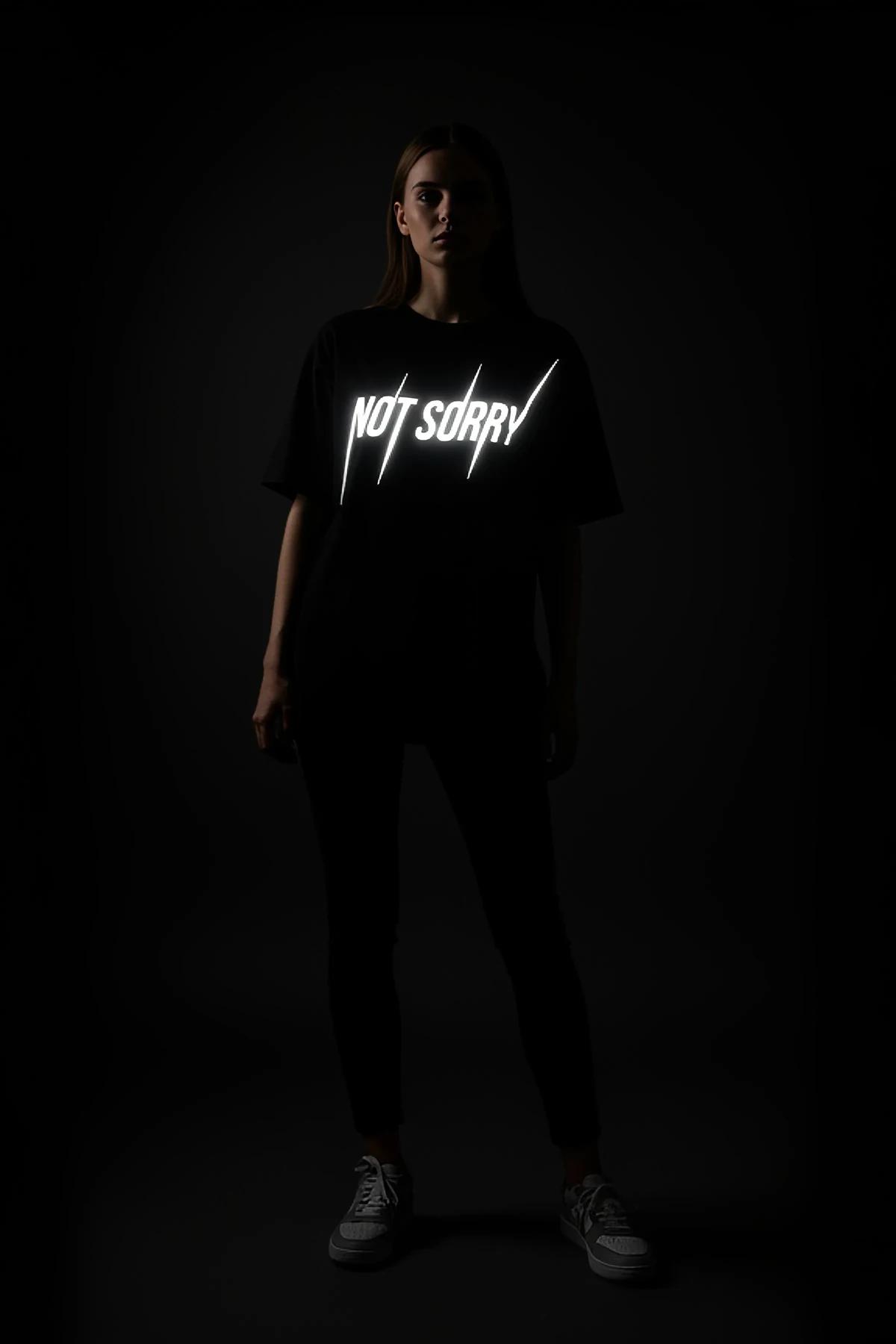 black cotton graphic tee with retroreflective NOT SORRY slogan front view daytime