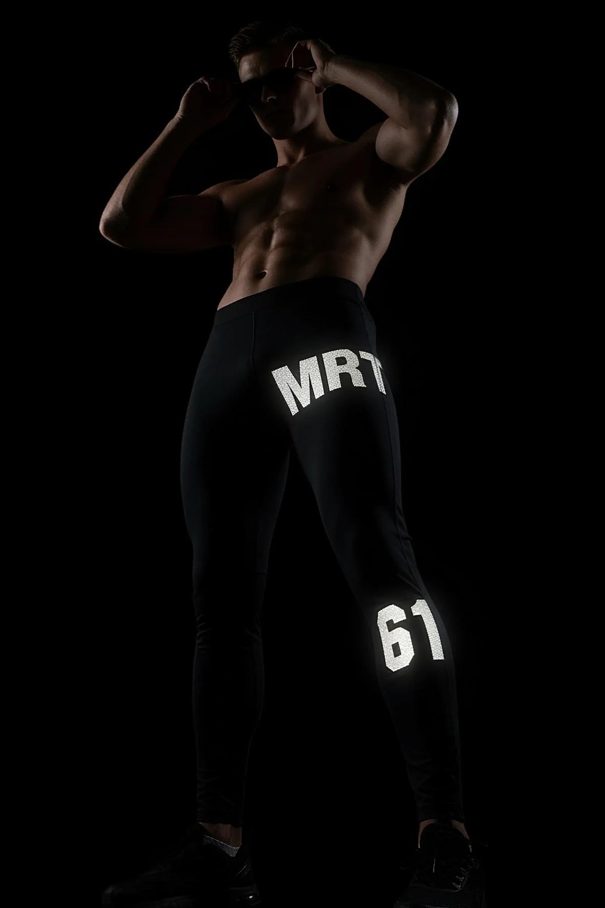 side view of black tapered joggers showing MRT and number 98 reflective print on leg