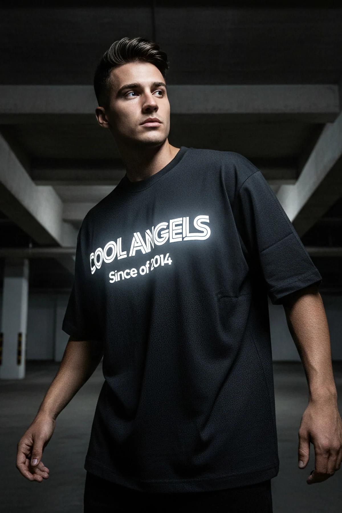 close-up of reflective COOL ANGELS block lettering glowing white-silver on black cotton t-shirt chest