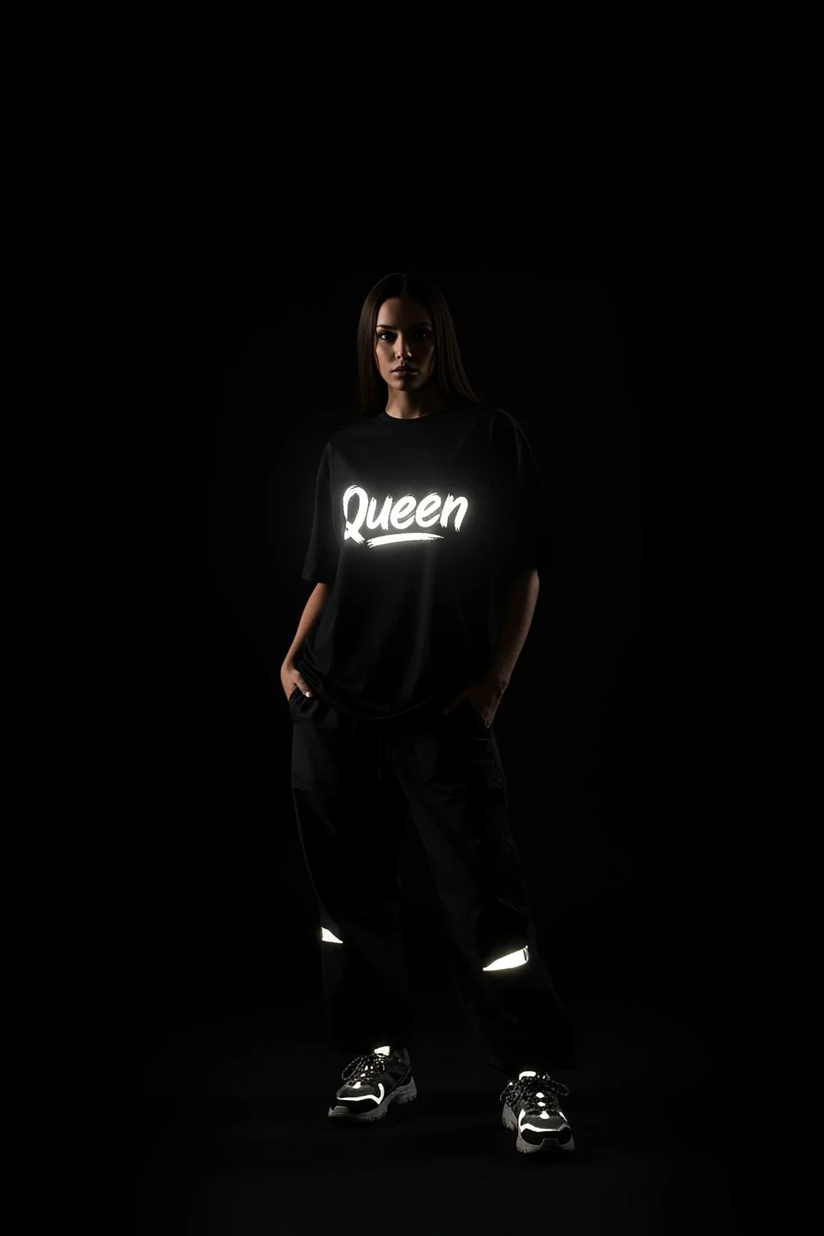 black oversized t-shirt back view with white retroreflective brush-script custom text graphic glowing in low light