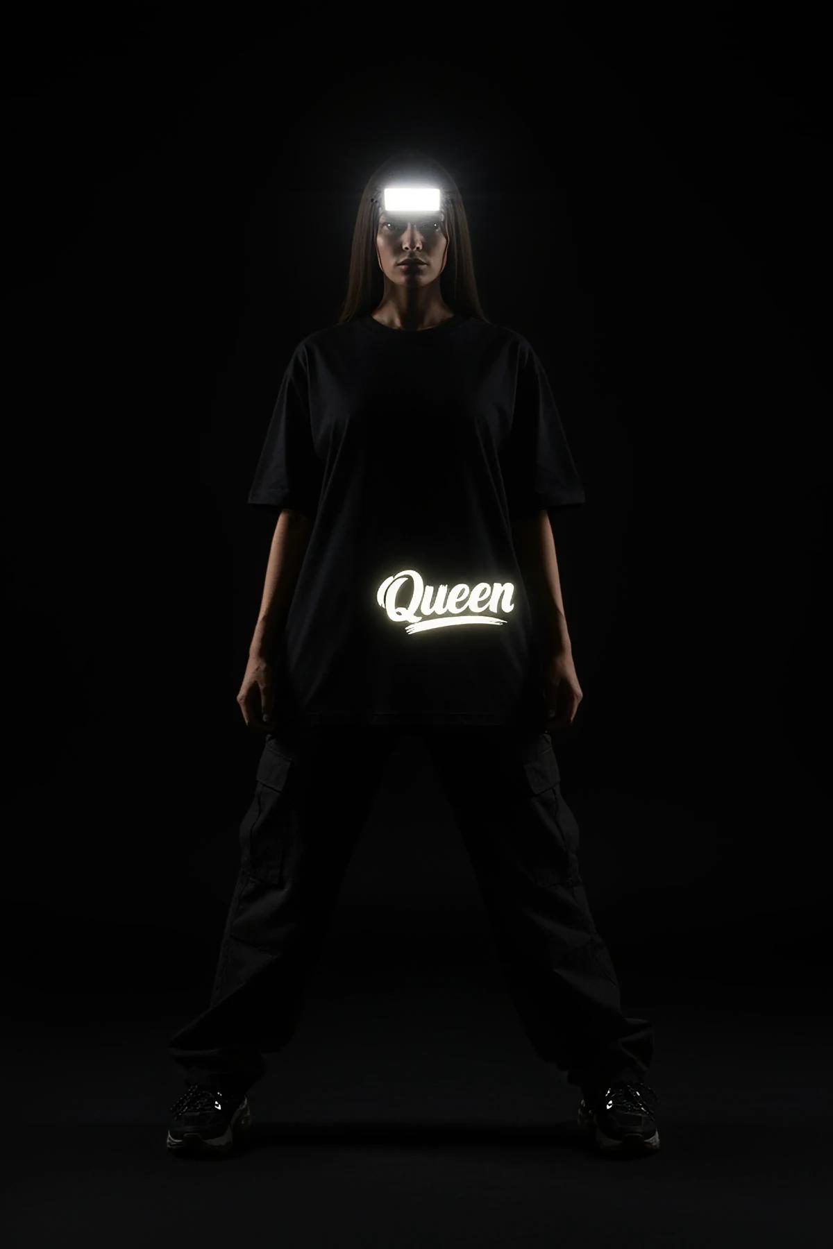 close-up of retroreflective brush-script lettering on black t-shirt back glowing white in dark environment