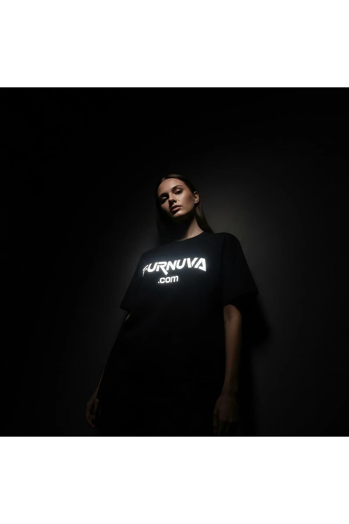 black oversized cotton t-shirt with bright white reflective graphic print glowing on chest in dark studio