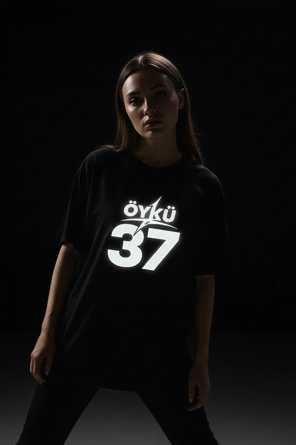 black oversized custom reflective graphic tee with personalized name and number print glowing in low light