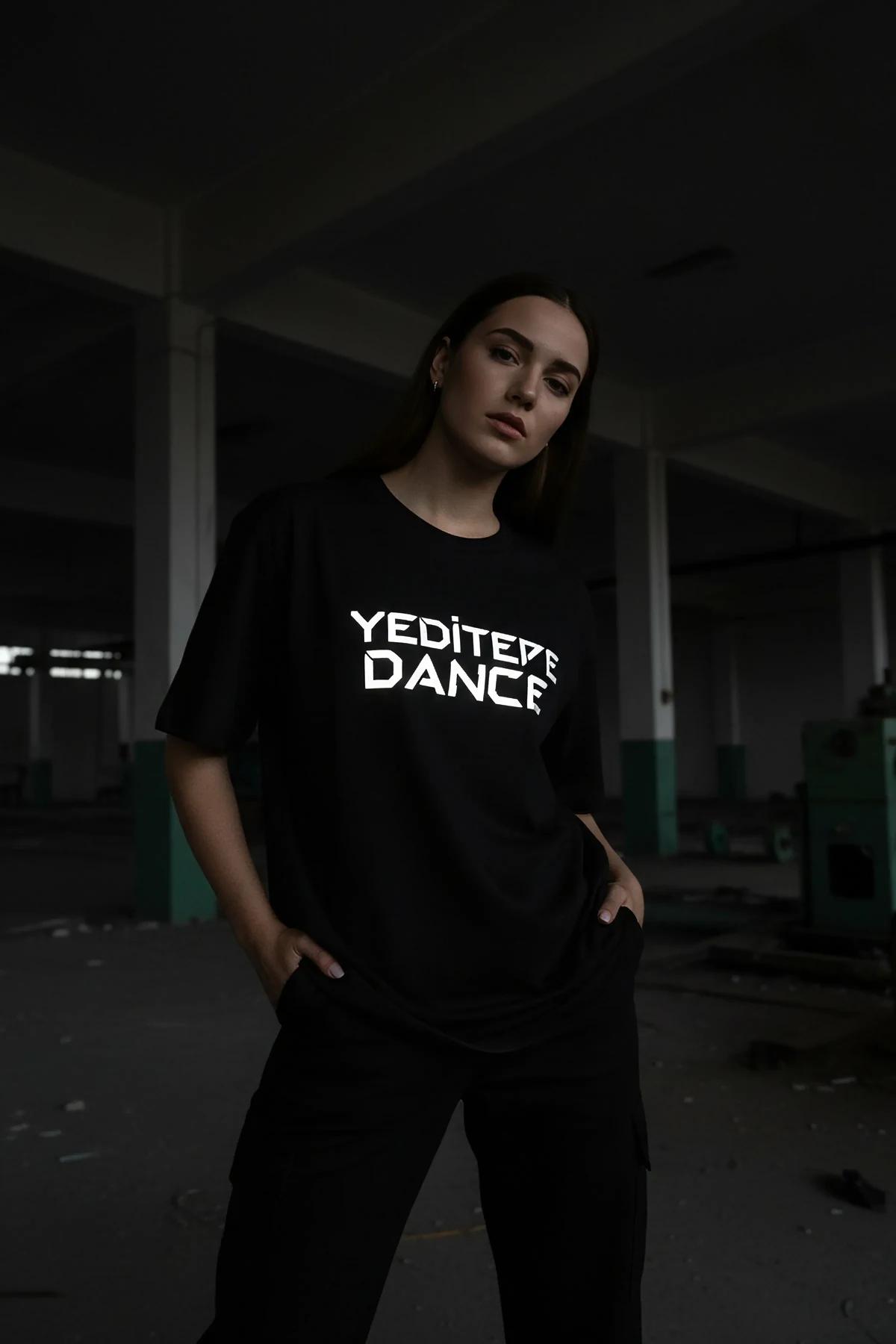 black oversized reflective graphic t-shirt with bright white custom chest print glowing under direct light
