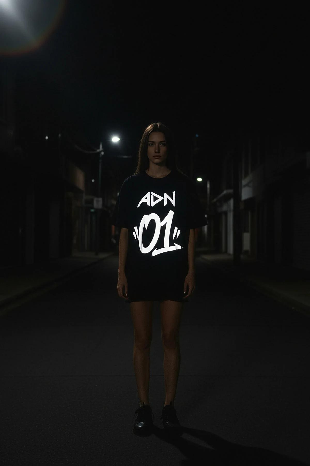 black oversized reflective graphic t-shirt with graffiti-style lettering glowing bright white under night street lighting