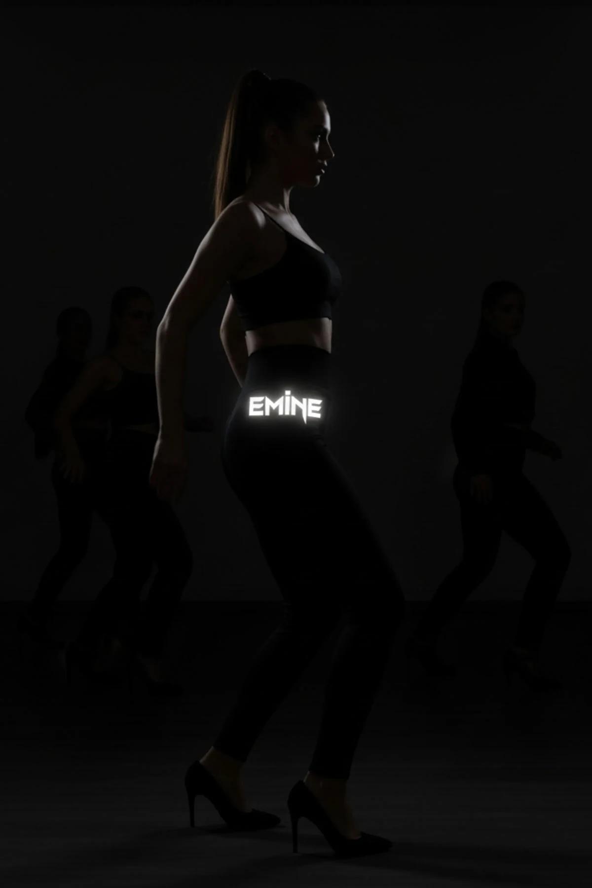 model wearing black glow leggings and black sports bra at night with FT M logo illuminated