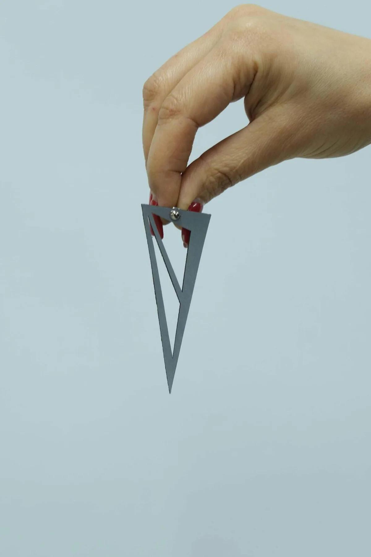 büyük beyaz üçgen küpe yakın çekim, lazer kesim iç geometrik açıklıklar ve reflektör kaplama detayı