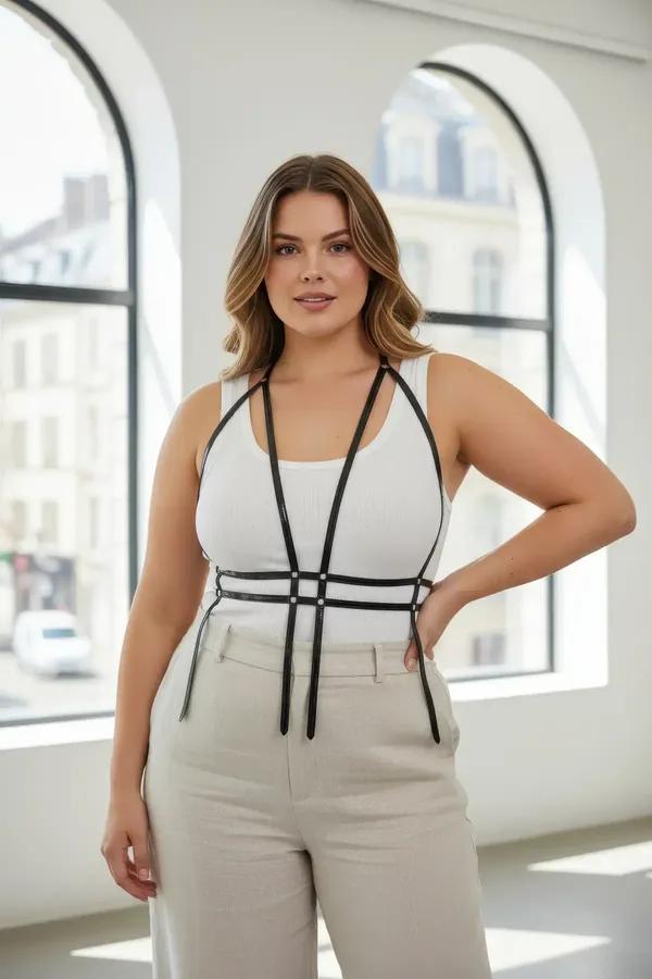 black faux leather caged harness with geometric chest strap grid and silver connector hardware worn over white top