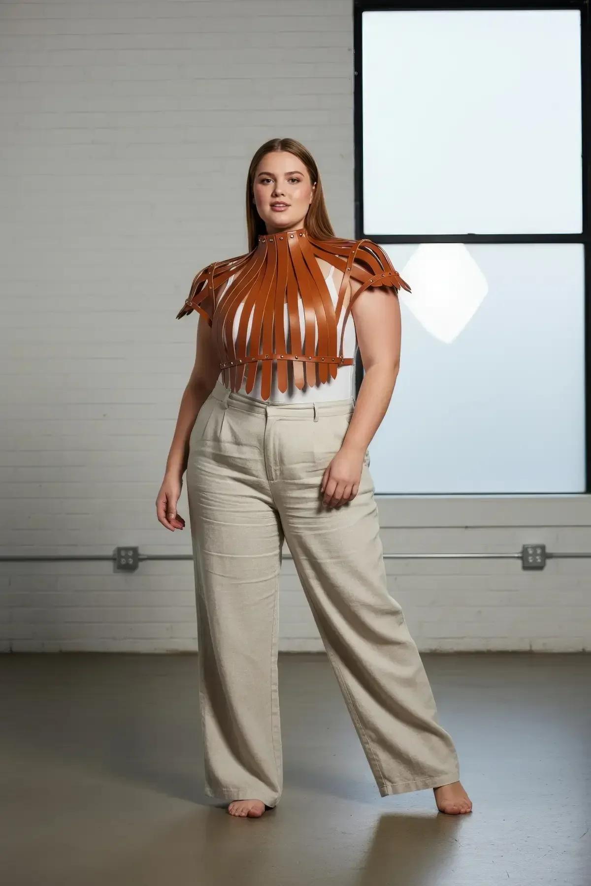 side view of tan faux leather harness top showing cap-sleeve shoulder tabs and waistband closure