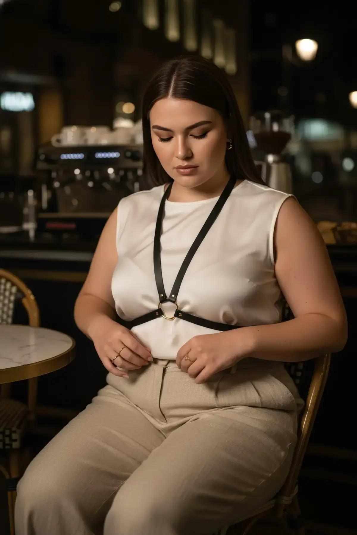 black underbust chest harness styled over blazer, gold O-ring at center chest, street fashion look