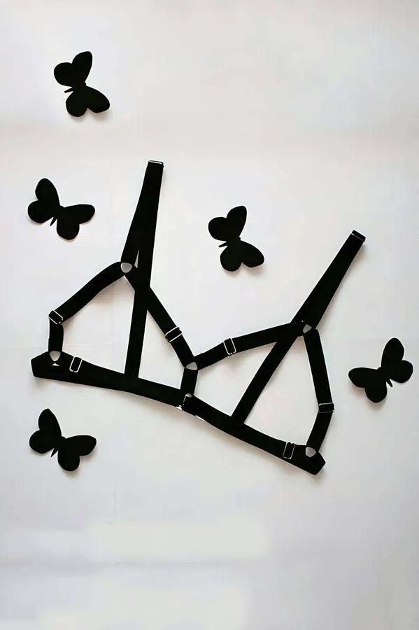 black elastic strappy cage bra harness with geometric triangular panels and silver slide buckle adjusters laid flat