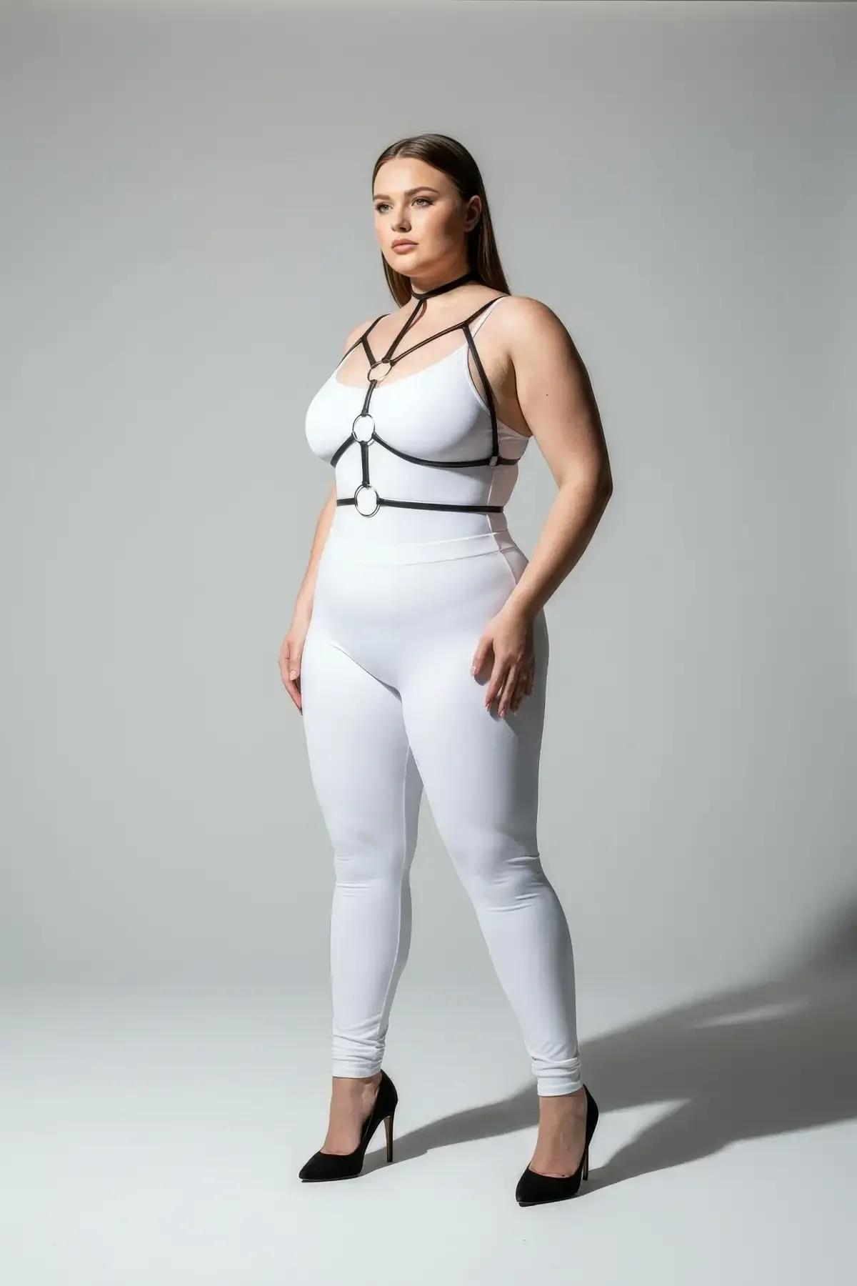 Front view of black strappy harness bra with two gold O-rings framing the bust, plus-size model