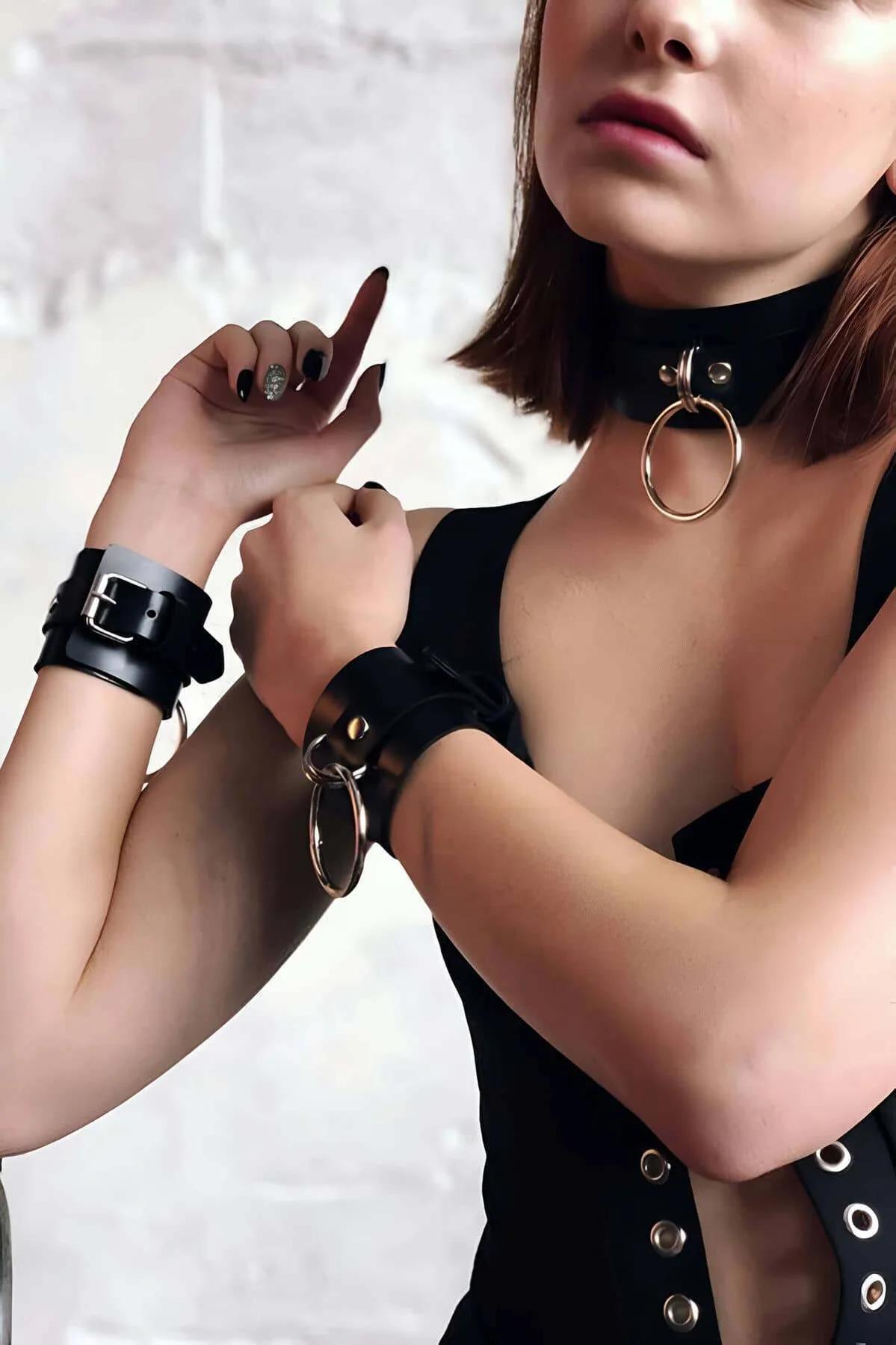 black faux leather choker collar large gold O-ring worn with matching black wrist cuffs silver buckle edgy gothic style