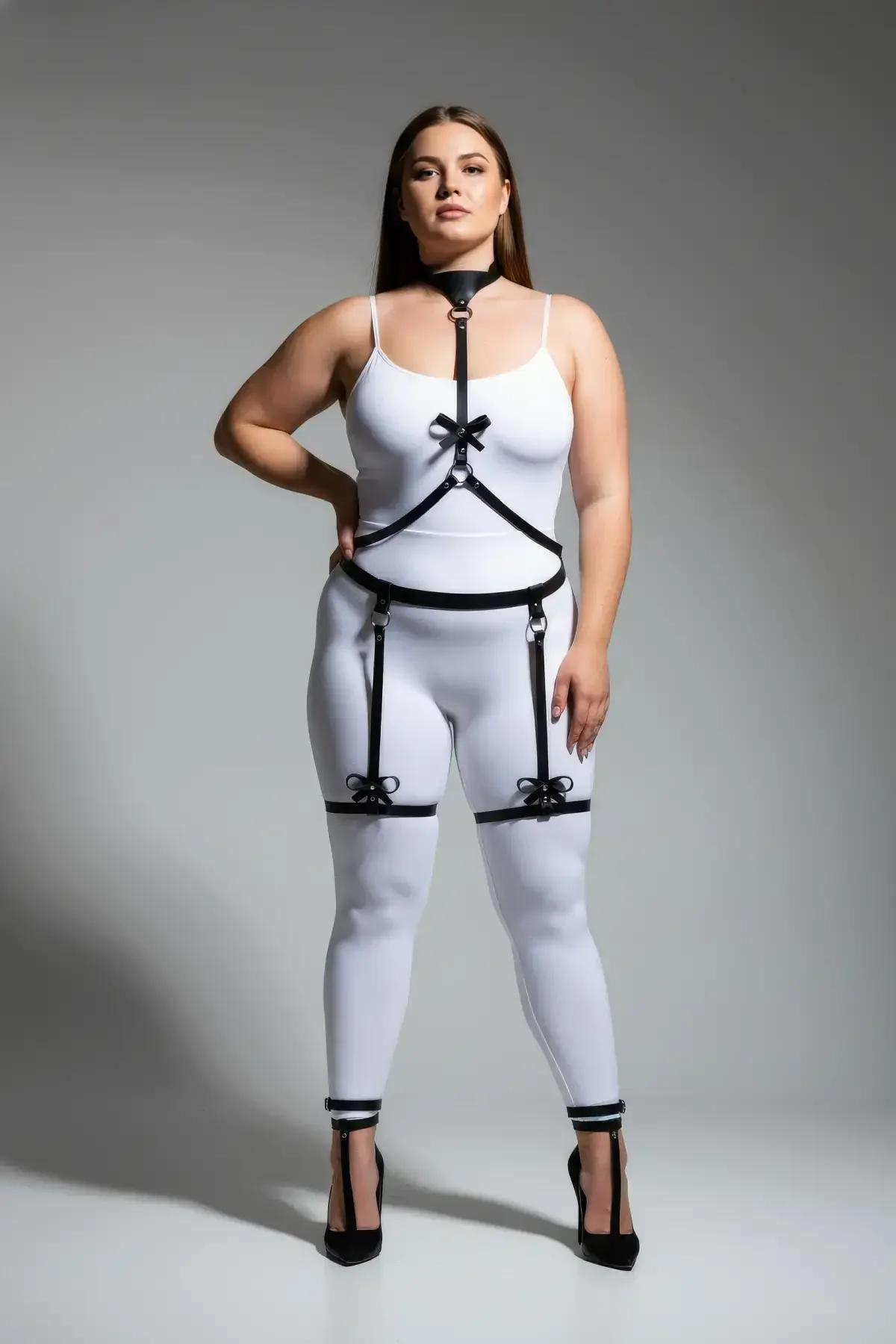 close-up of black faux leather chest straps with satin bow at sternum and silver hardware