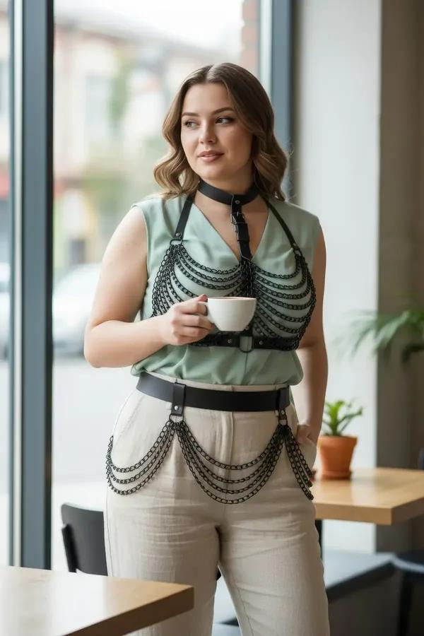 Black faux leather full body harness with multi-row draped chain chest overlay, choker collar, and wide waist belt with hip c