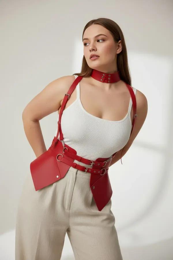 Red faux leather corset waist harness with O-rings and matching studded choker set worn over cream top