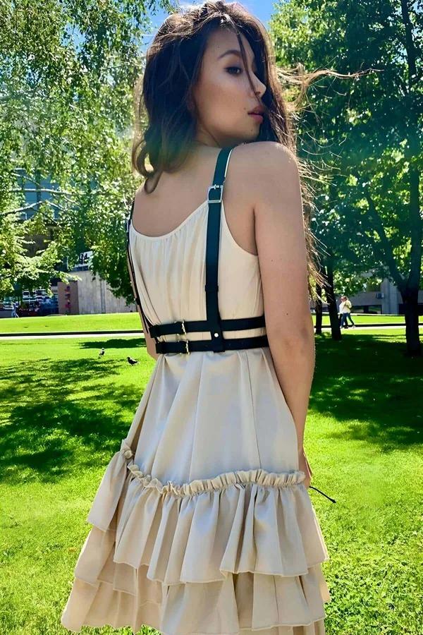 Siyah ince faux deri bantlı göğüs harness kemer, krem rüflü elbise üstünde X-cross O-ring detay
