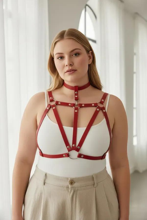 Red vegan leather chest harness with integrated choker and silver O-rings, strappy geometric cage design on plus-size model