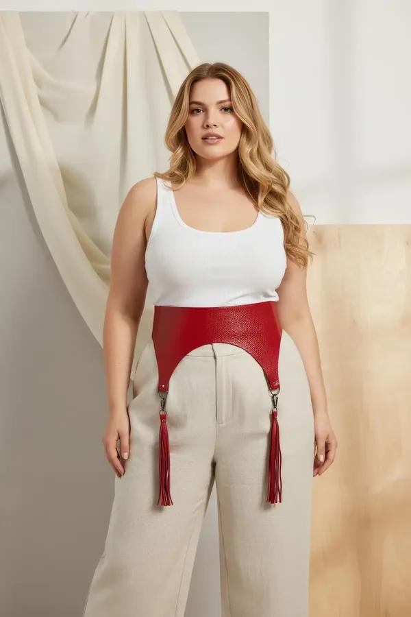 red wide faux leather waist belt harness with matching red tassels and silver hardware worn over white tank and beige skirt