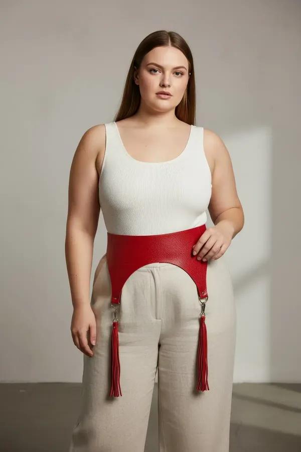 red wide faux leather waist belt harness with matching red tassels and silver hardware worn over white tank and beige skirt