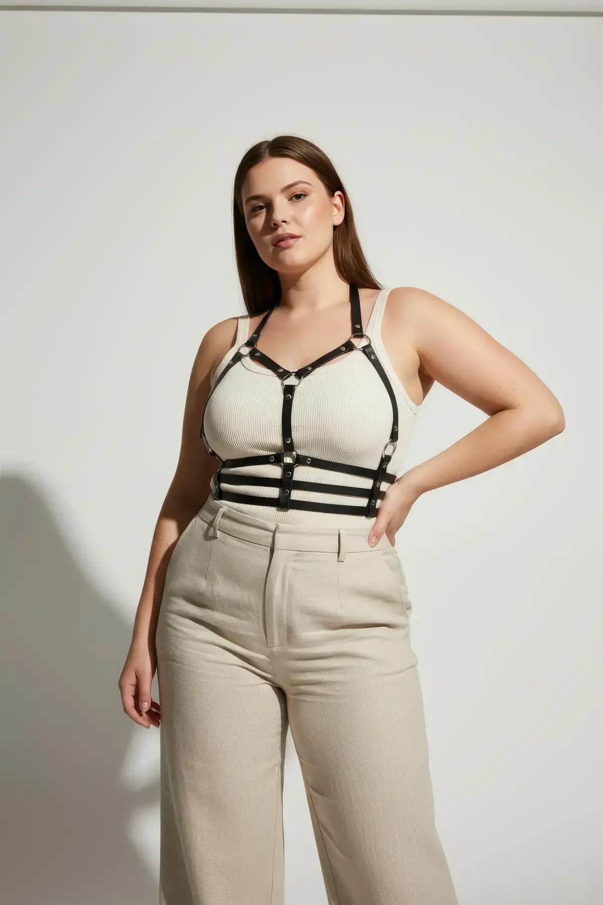 Black studded chest harness layered over neutral tank top casual streetwear styling
