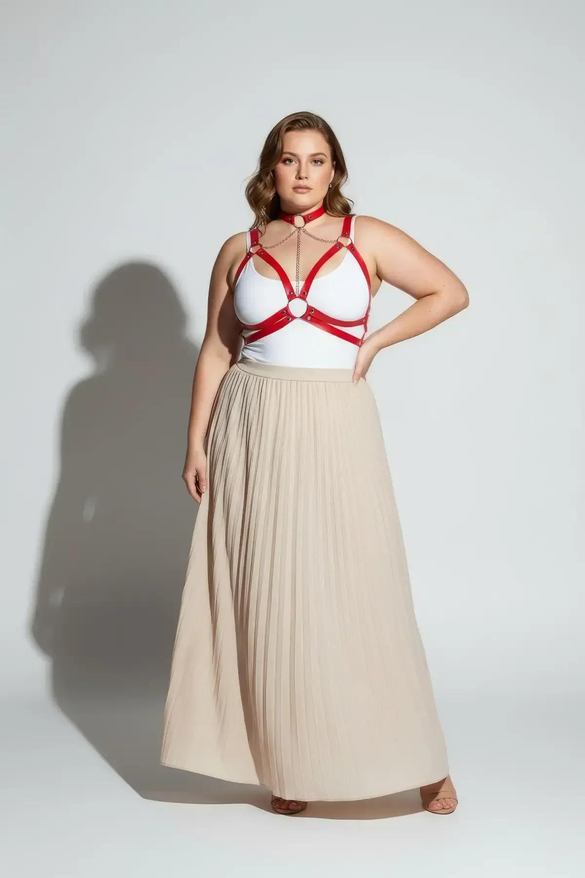 Plus-size red faux leather strappy harness with gold hardware, styled over white crop top, daytime look