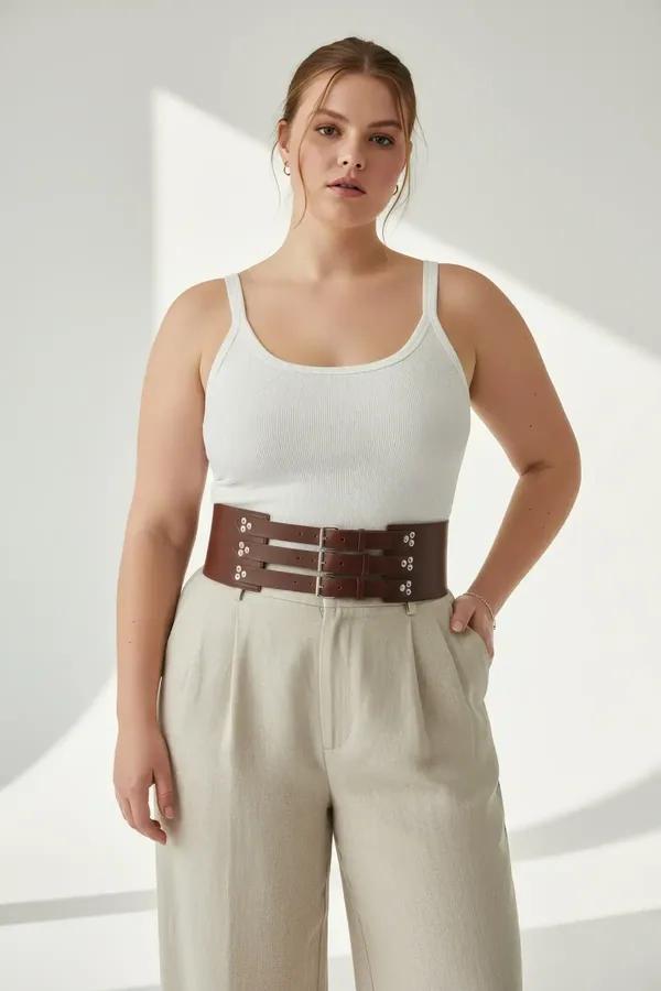 Cognac faux leather triple buckle waist cinch corset belt worn over white tank and wide-leg trousers