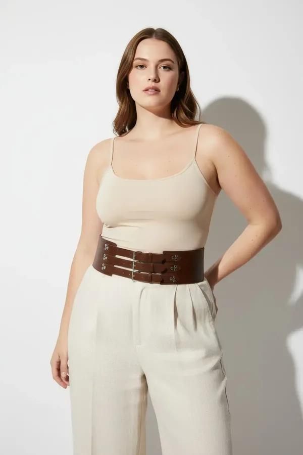 Cognac faux leather triple buckle waist cinch corset belt worn over white tank and wide-leg trousers