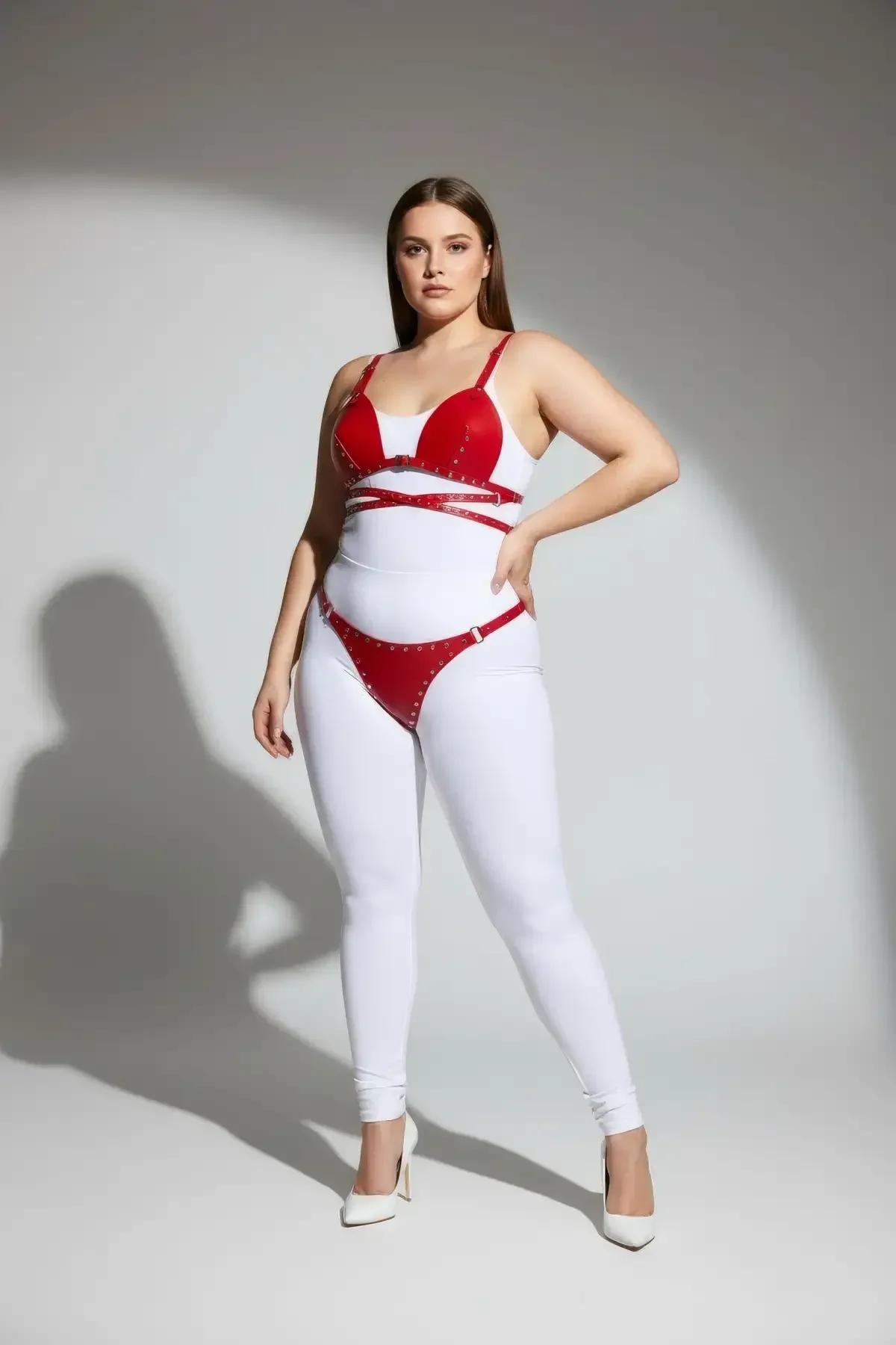 Crossover X-pattern studded straps bridging red bra harness top and waist band, close-up