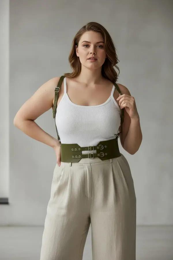 olive green wide faux leather waist harness with adjustable shoulder straps and silver buckle hardware worn over white tank t