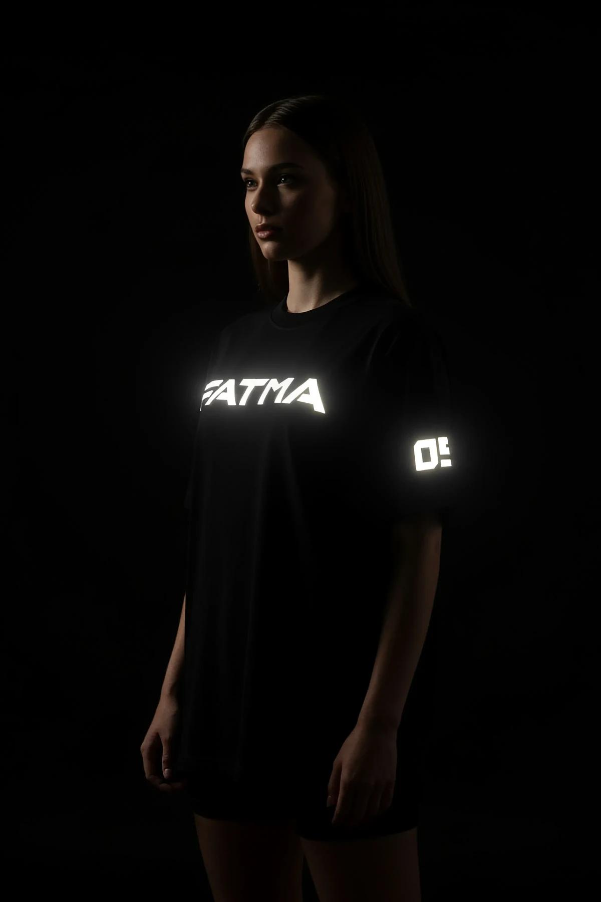 black oversized t-shirt with white reflective custom text print glowing against dark background