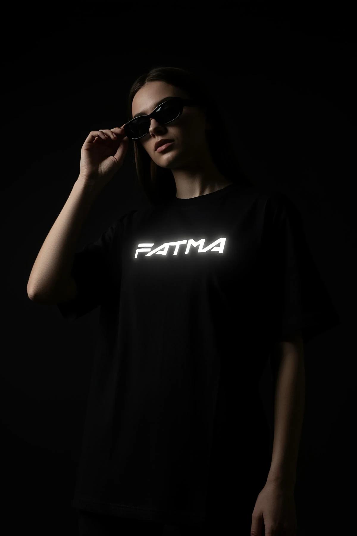 black oversized t-shirt with white reflective custom text print glowing against dark background