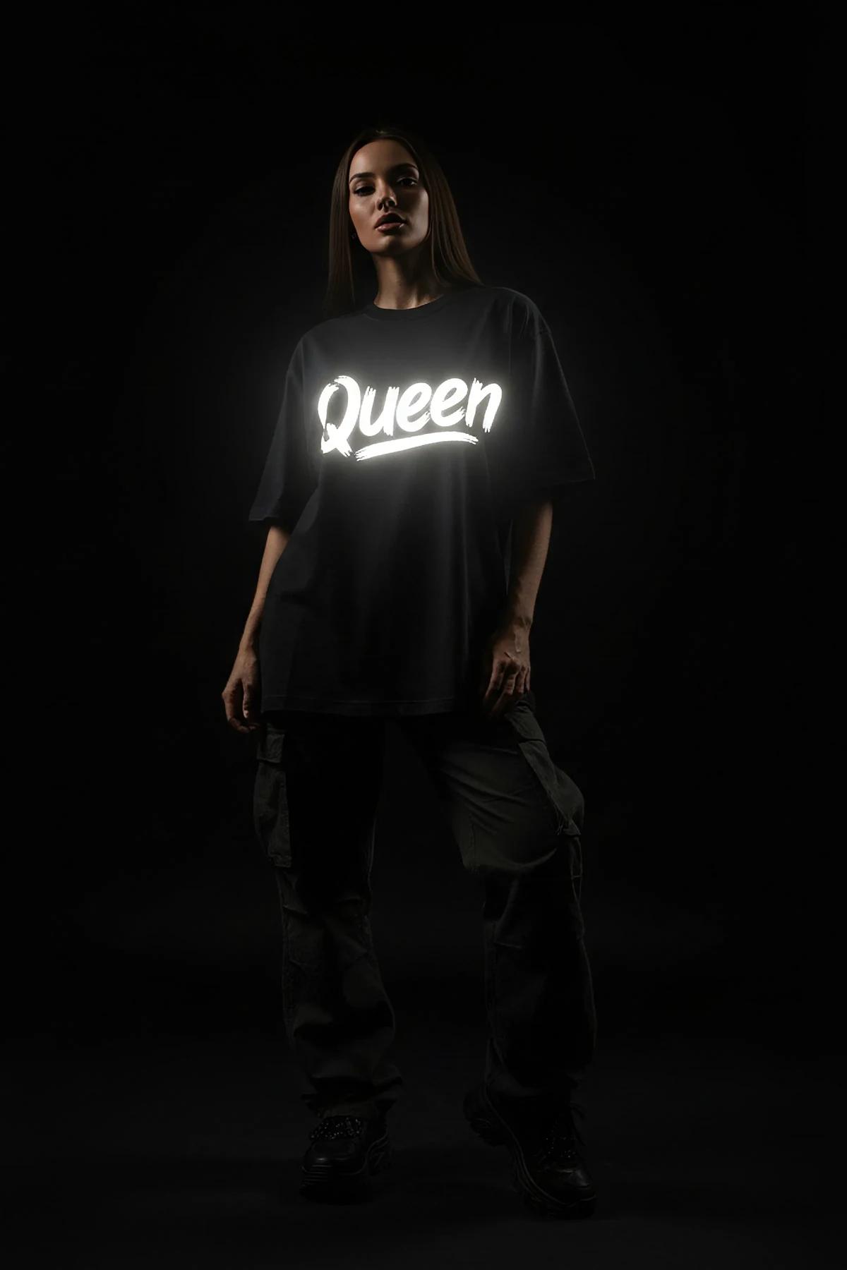 black oversized t-shirt back view with white retroreflective brush-script custom text graphic glowing in low light