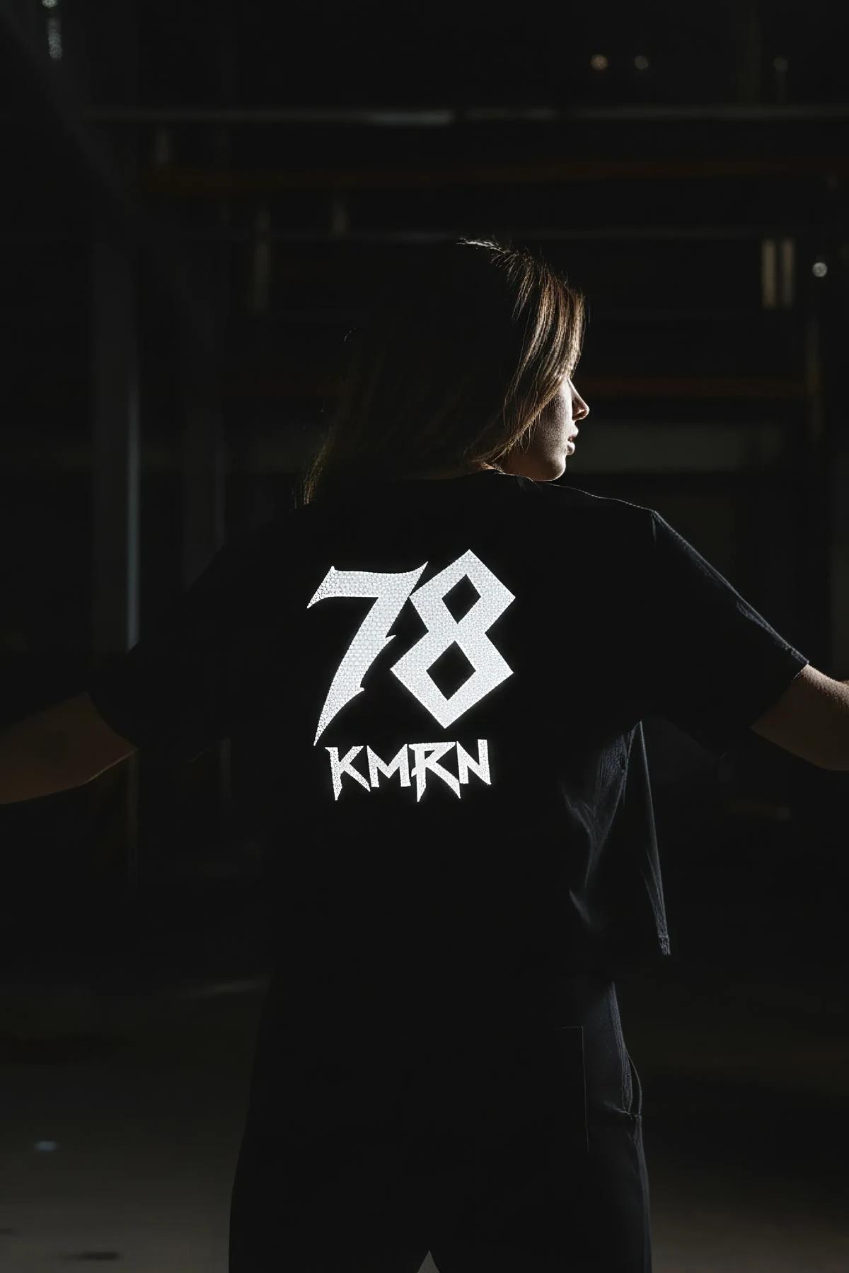black reflective custom graphic t-shirt back view with bold gothic name and number print glowing white in low light