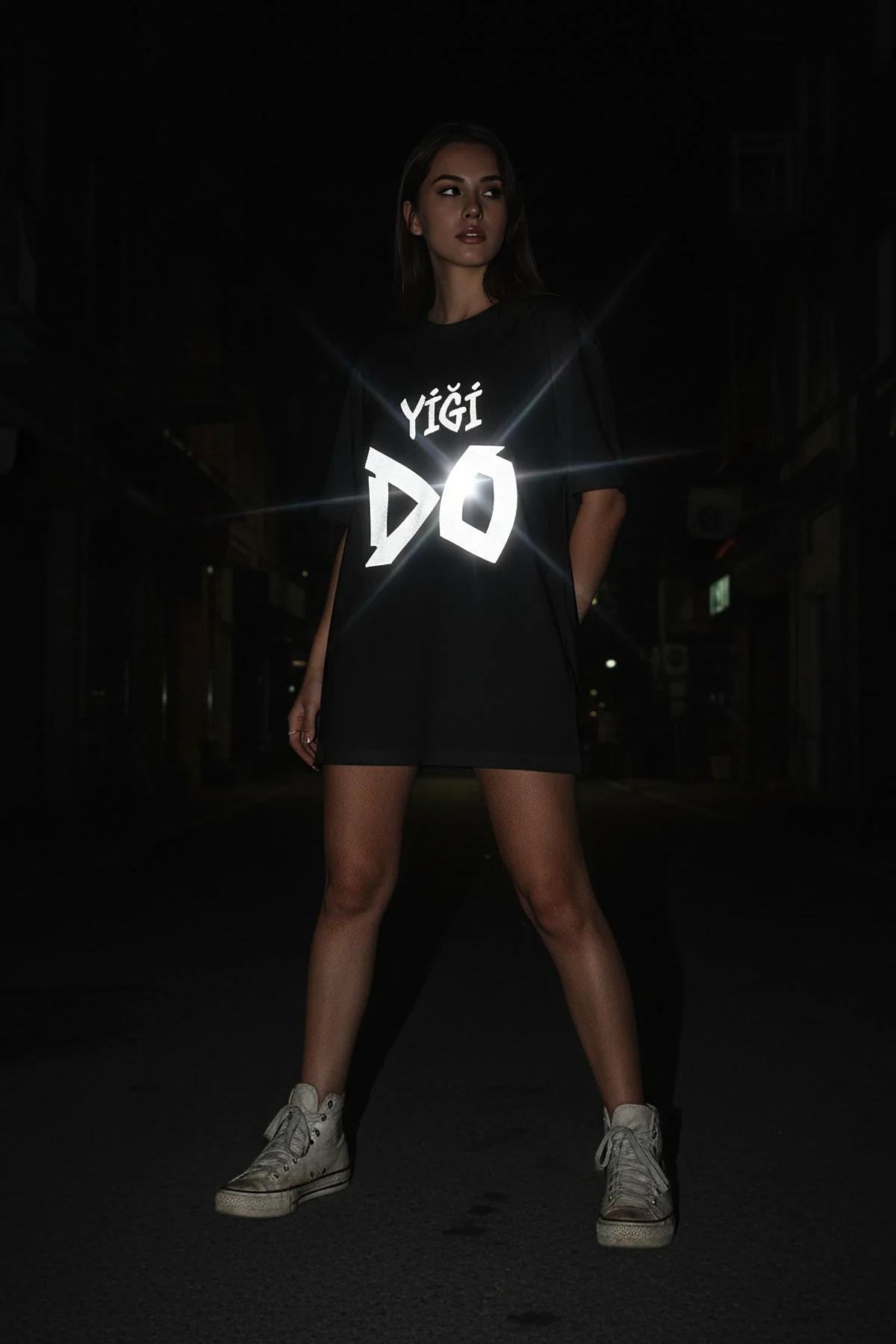 black reflective graphic t-shirt with bold white geometric typography print glowing in dark urban setting
