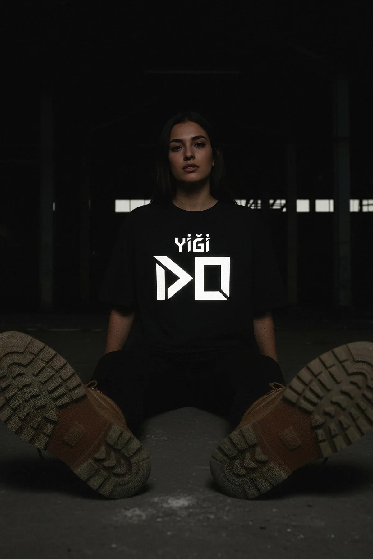 black reflective graphic t-shirt with bold white geometric typography print glowing in dark urban setting