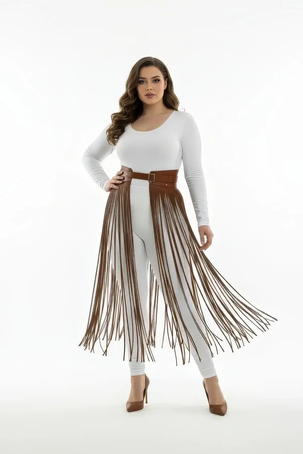 Brown faux leather waist harness skirt with long cascading fringe tassels over white leggings, gold buckle detail
