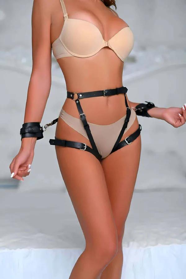 Siyah vegan deri popo saran harness takım altın tokalı ve bilek kelepçeli kadın modeli üzerinde