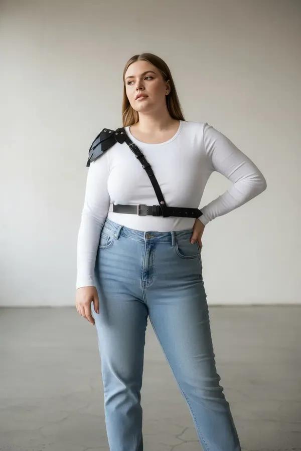 Black faux leather shoulder harness with tiered epaulette and wide waist belt worn over white tank top