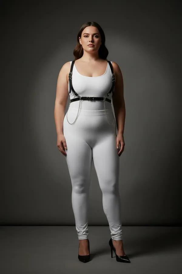 black faux leather chest harness with detachable silver waist chain worn by plus-size model over white bodysuit