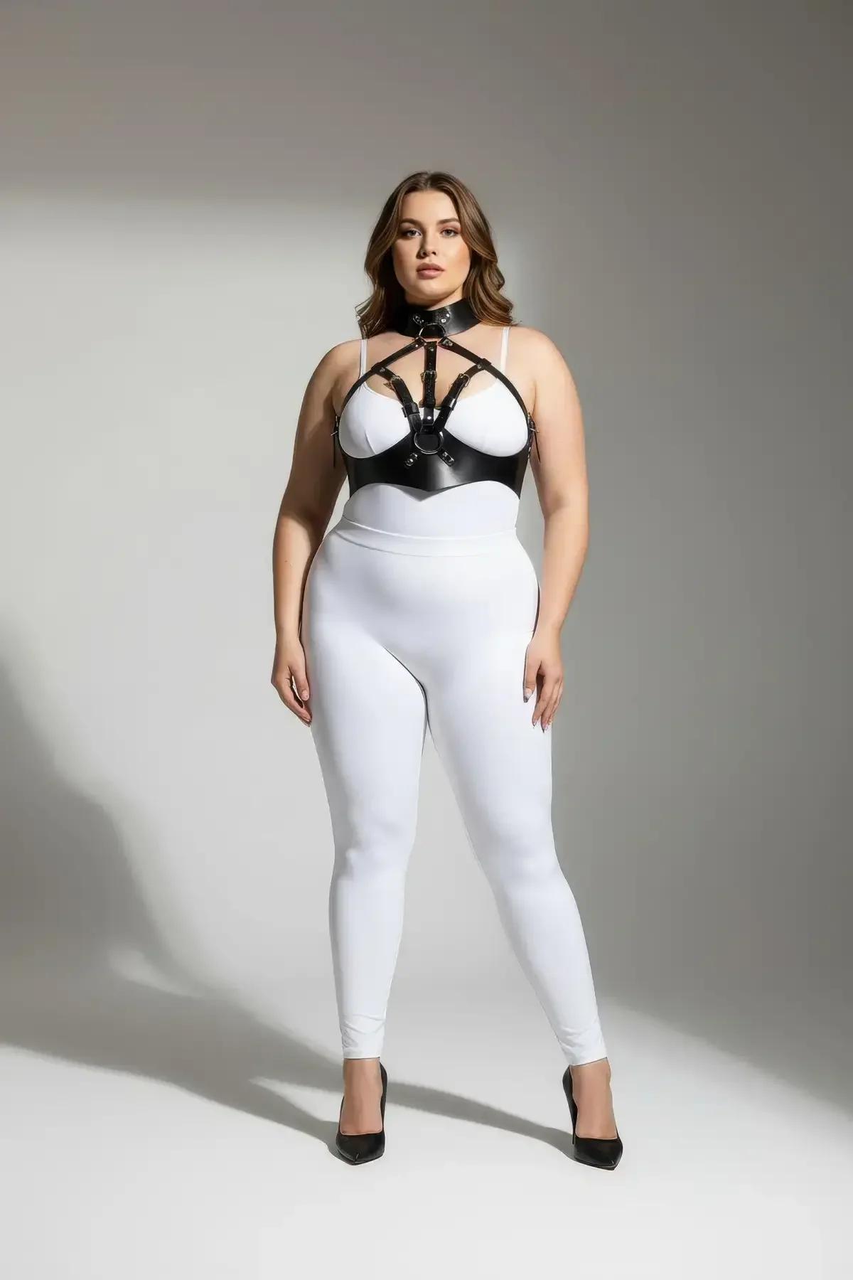 black faux leather body harness with high collar and silver O-ring worn over white bodysuit, plus-size model, cage strap ches