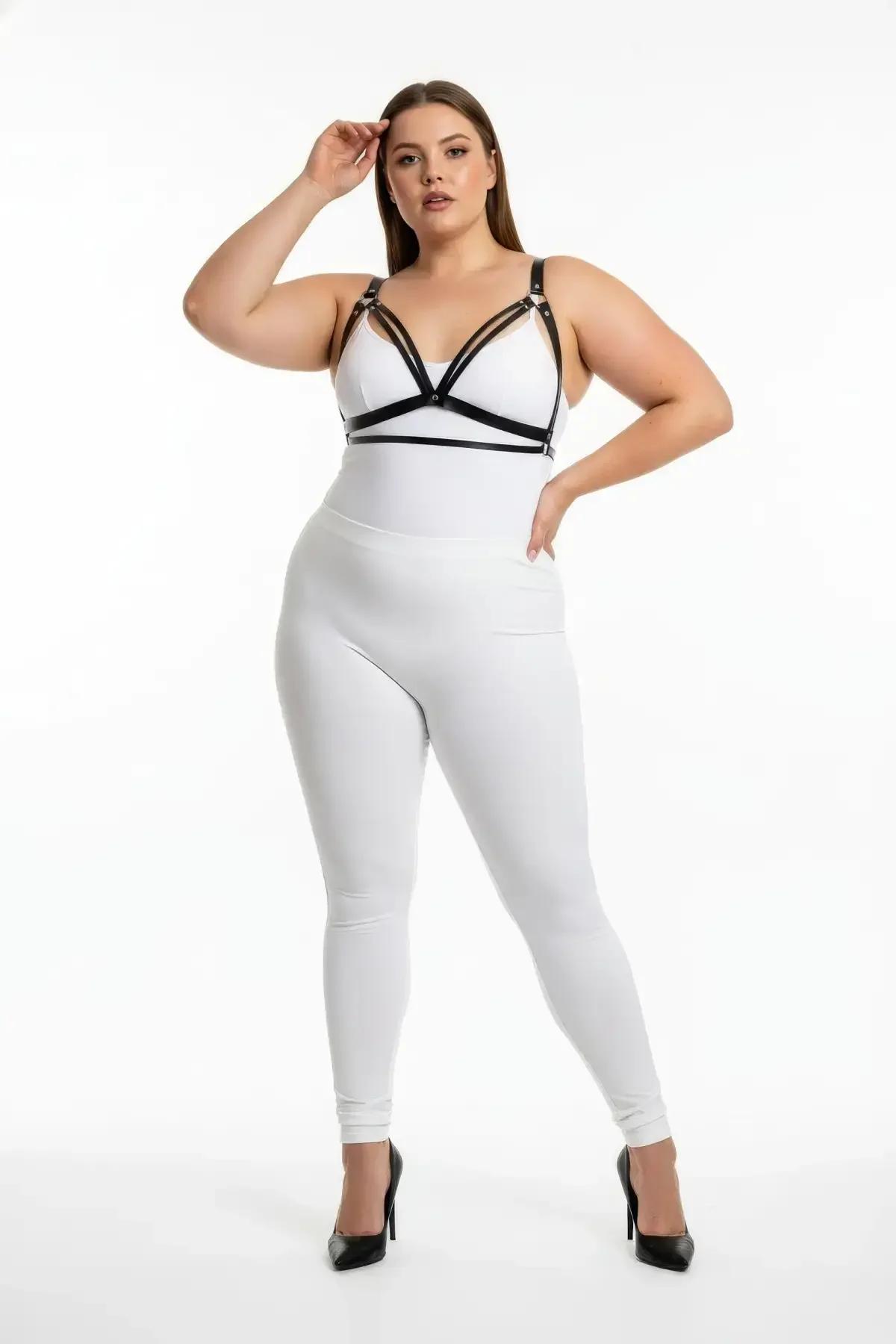 black faux leather harness bra with triple V-chest straps and silver buckles worn over white bodysuit