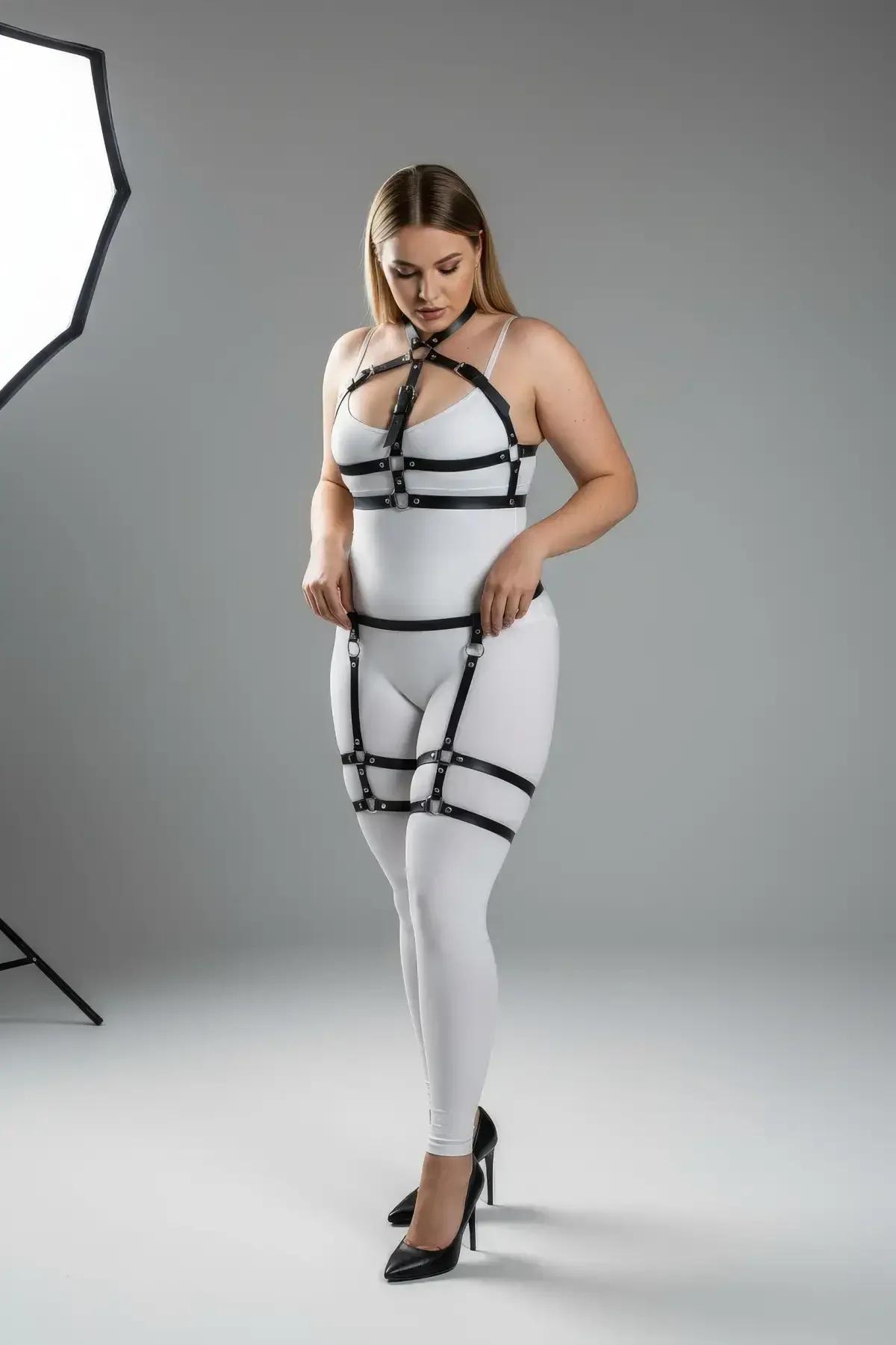Black faux leather full body harness with garter straps, thigh bands, and silver O-ring hardware on plus-size model