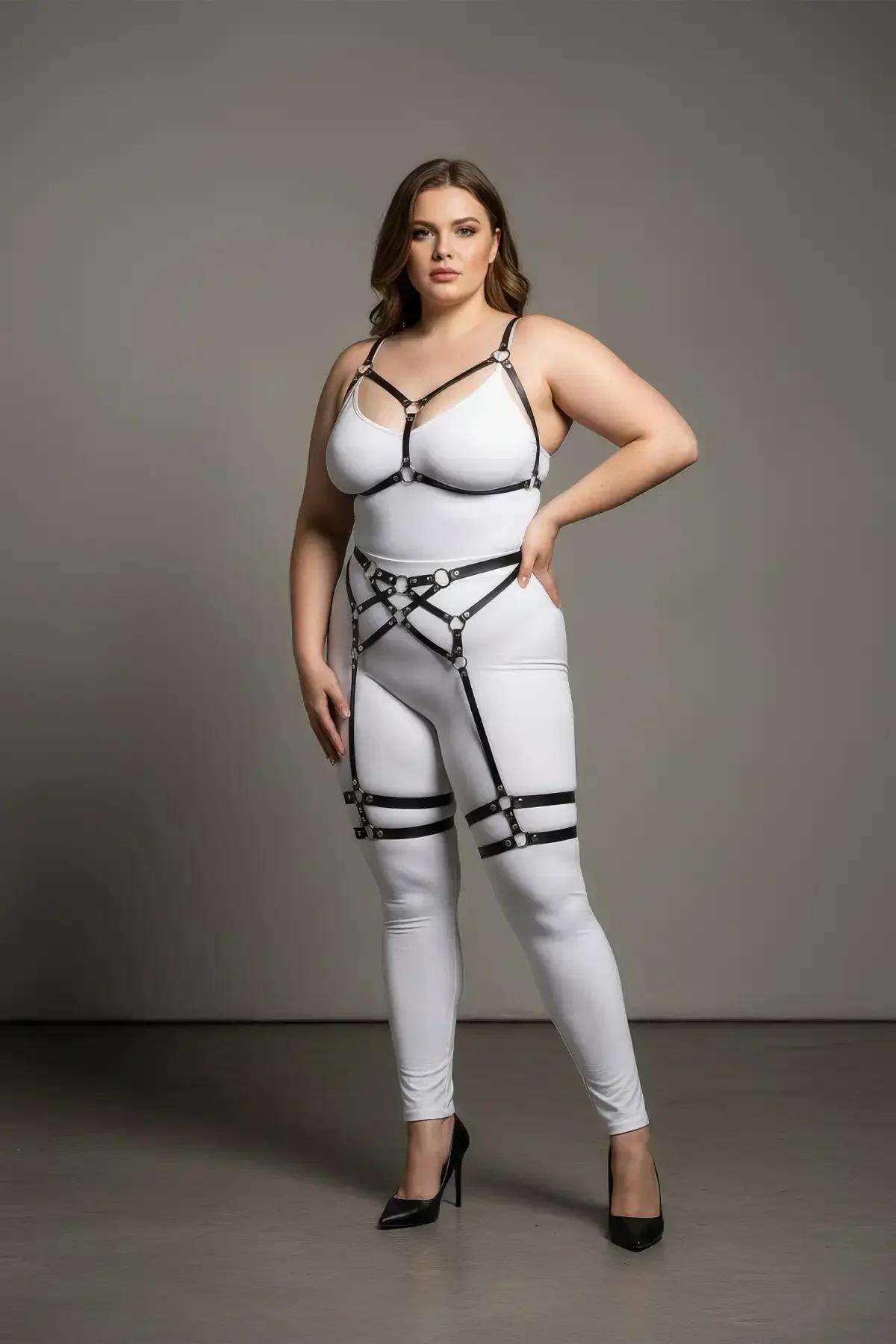 Black faux leather full body harness with chest V-frame, waist cage, and dual thigh garter bands on plus-size model