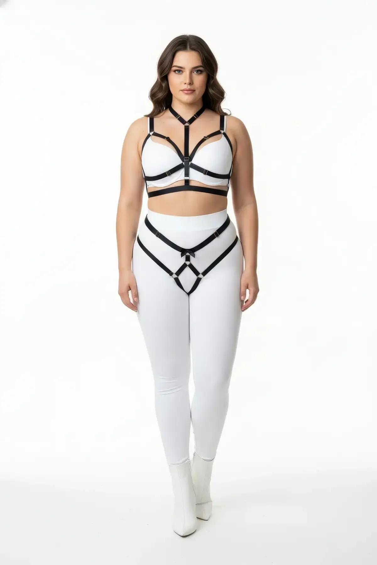 black vegan leather body harness and garter belt set with silver O-rings worn over white leggings, plus size model
