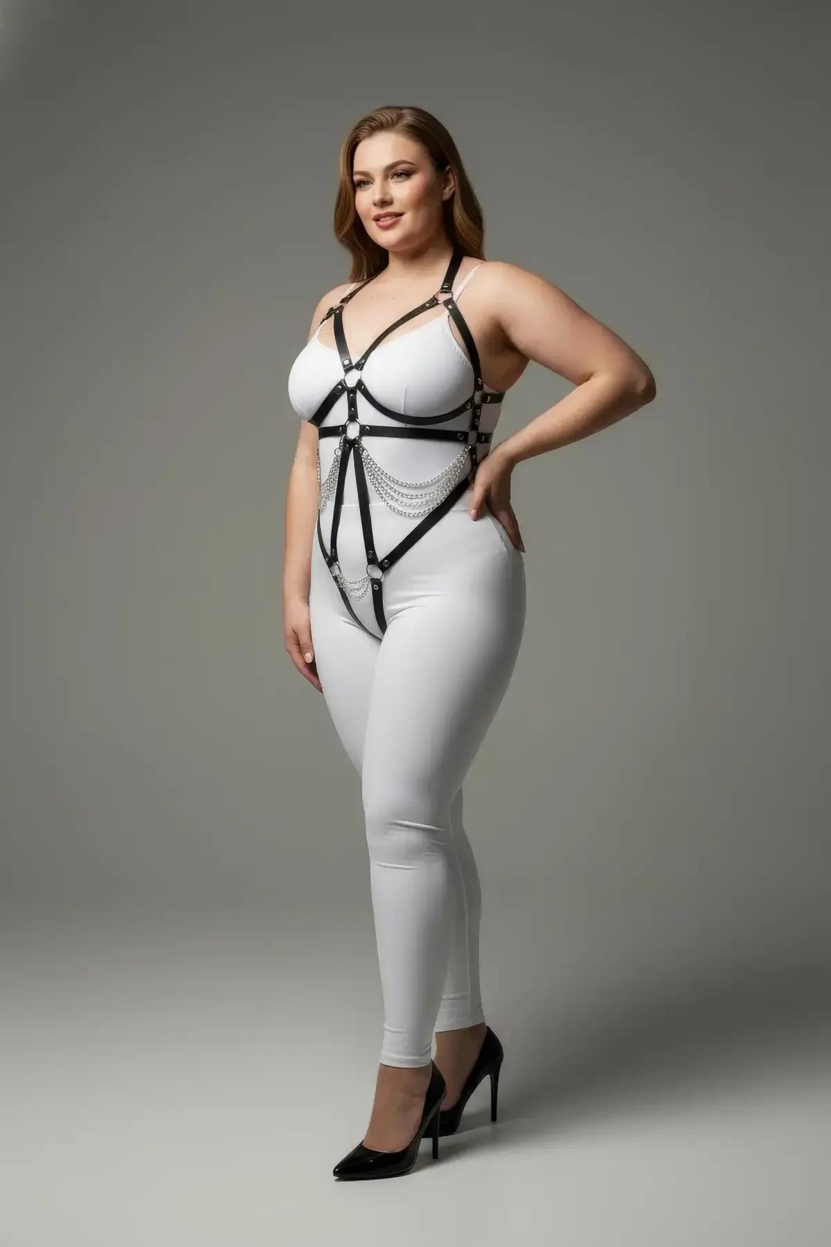 black faux leather strappy underbust harness with silver draped chains and O-ring closure worn over white bodysuit