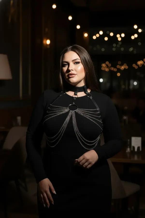 Black faux leather chain body harness with choker collar and cascading silver O-ring chains worn over black dress